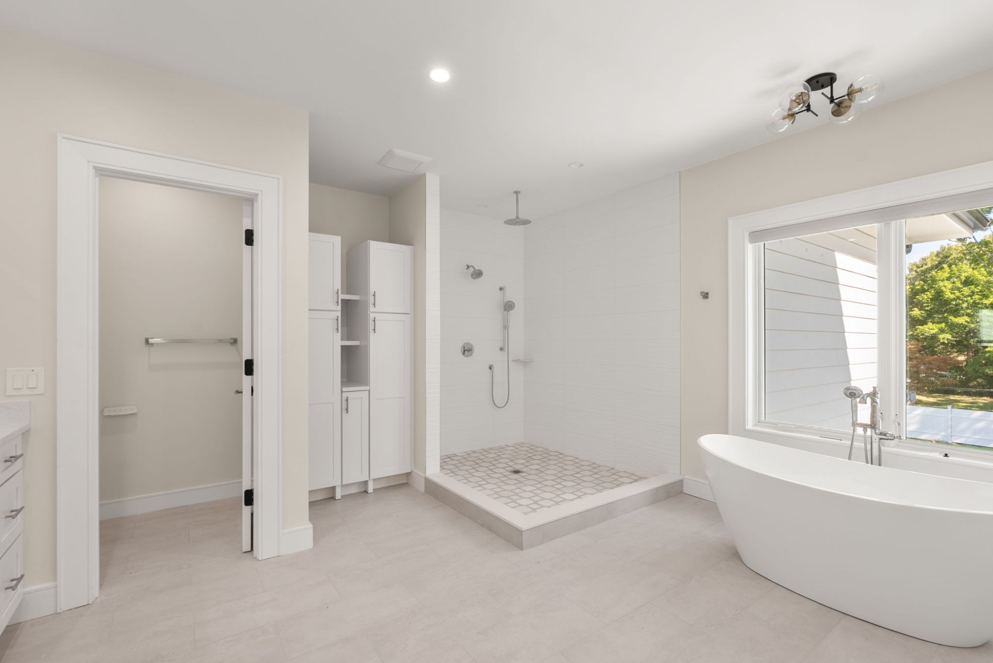 Primary bath with a curbed walk-in shower, rain head and linen cabinets